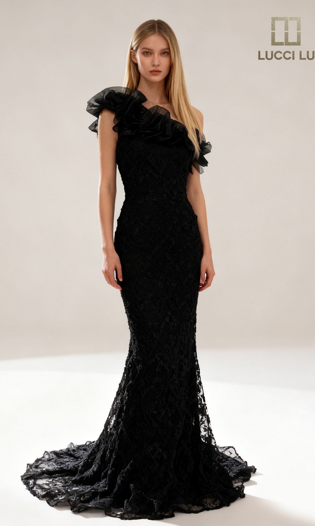 Woman in the Lucci Lu 6062 long black prom dress featuring a fitted silhouette and one-shoulder lace with ruffled detail, standing against a neutral background. LUCCI LU logo appears in the top right corner.